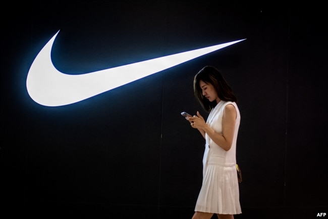 Nike дүкенінің алдынан өтіп бара жатқан тұрғын. Пекин, 2 маусым 2021 жыл.