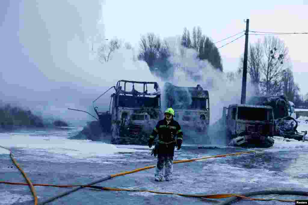 Пожежник проходить перед напівпричепами, знищеними під час російських нічних ударів безпілотників та ракет по Києву. Київ, 24 січня 2026 року