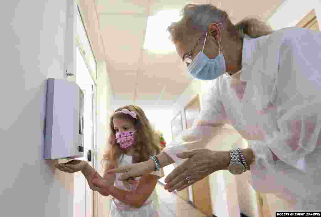 A health worker shows a little girl how to use a hand sanitizer during the first day of school at the George Enescu National College of Music in Bucharest, Romania, on September 14.