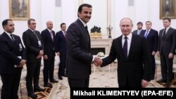 Russian President Vladimir Putin (front right) shakes hands with Emir of Qatar Sheikh Tamim bin Hamad al-Thani (front left) at the Kremlin.