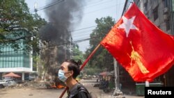 Оппозициялык "Демократия үчүн улуттук лига" уюмунун желегин көтөргөн демонстрант. Янгон шаары, Бирма. 2021-жылдын 27-марты.