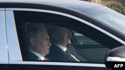 In this pool photograph distributed by Russian state agency Sputnik, Azerbaijan's President Ilham Aliyev (R) and Russia's President Vladimir Putin (L) drive a car following their talks in Baku on August 19, 2024.