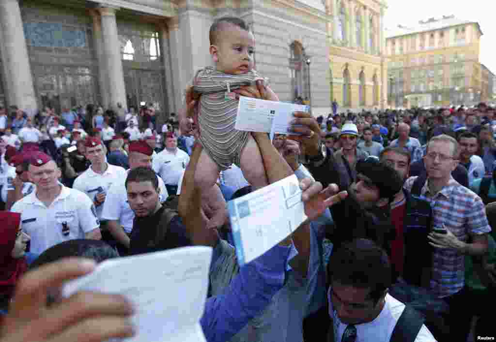 Migrants wave their train tickets and lift up children outside the main Eastern Railway station in Budapest. Hungary closed Budapest's main station on September 1 with no trains departing or arriving until further notice. There are hundreds of migrants waiting at the station. The arrival of hundreds of thousands of migrants has sparked a crisis in Europe, with the EU being criticized for doing little to solve the problem. (Reuters/Laszlo Balogh)