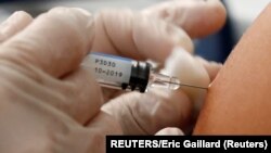 A doctor vaccinates a patient as part of the start of the seasonal influenza vaccination