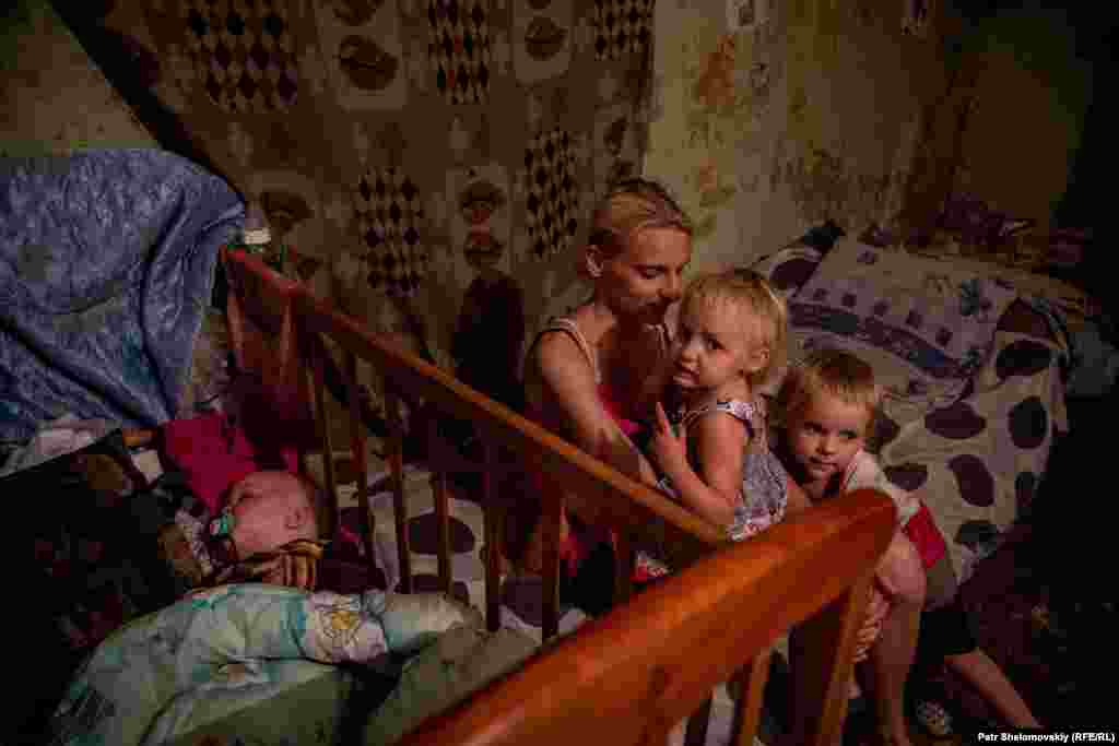 Svetlana sits with her three children. The youngest is less than a year old.