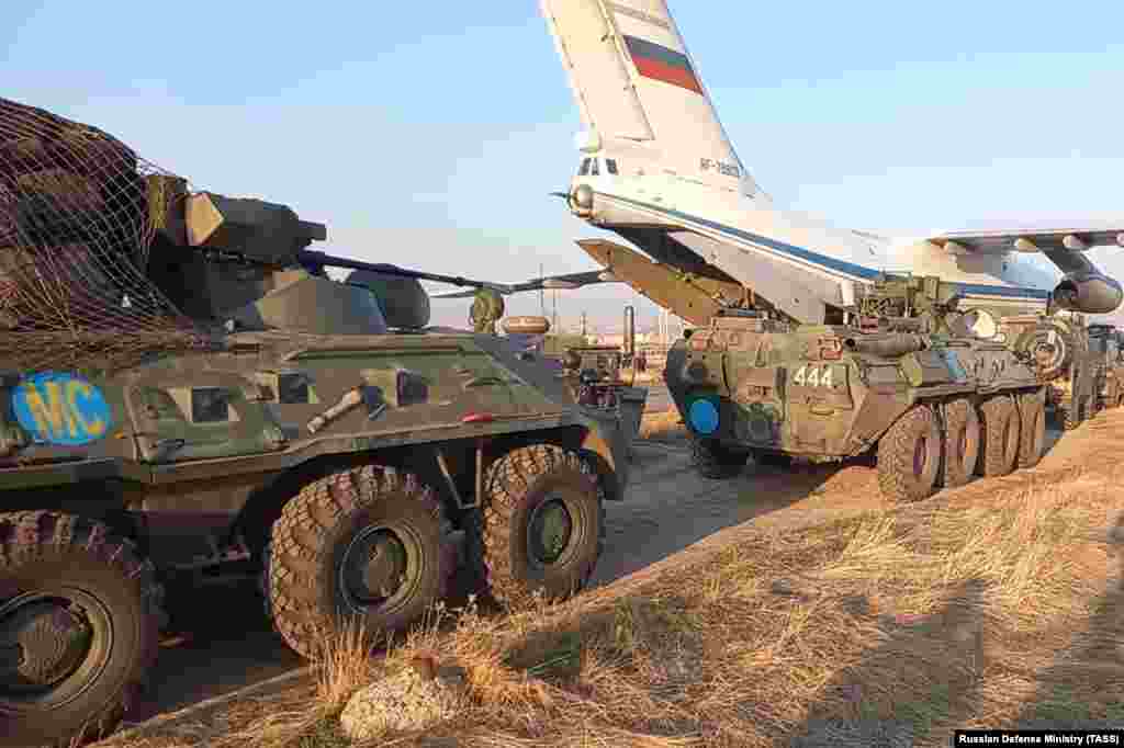 Military vehicles stand next to a plane as Russian peacekeepers arrive at an airport outside Yerevan on November 11. While the announcement of the cease-fire deal triggered celebrations in Azerbaijan, it sparked angry protests in Armenia, with demonstrators storming government buildings and parliament.