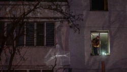 Un bărbat ține o lanternă la fereastra apartamentului său, noaptea, în timpul întreruperii livrării de energie electrică la Varnița, pe 17 ianuarie 2025. 