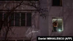 Un bărbat ține o lanternă la fereastra apartamentului său, noaptea, în timpul întreruperii livrării de energie electrică la Varnița, pe 17 ianuarie 2025. 