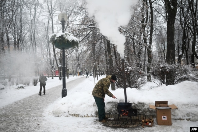 Një vullnetar vendos një stufë në një park publik në Kiev, në mënyrë që qytetarët të mund të përgatisin ushqime.