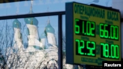A board showing currency-exchange rates is on display in a street, with a church reflected in a shop window in Moscow on January 6.