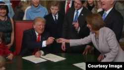 U.S. President Donald Trump hands out pens as he signs bills shortly after his inauguration on January 20.