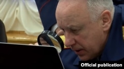 Глава Следственного комитета Александр Бастрыкин с лупой у экрана компьютера.
