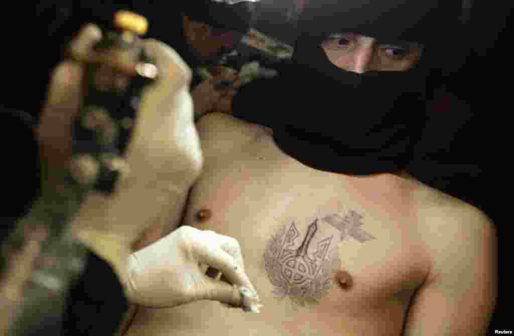 یکی از مخالفان دولت در &laquo;کی یف&raquo; در حال زدن نقش خالکوب صیلب سلتیک روی بدن. صلیب سلتیک علامت گروه های راست افراطی به شمار می آید