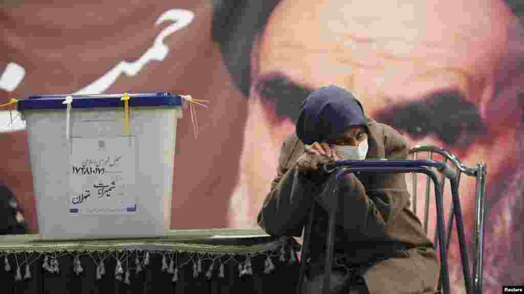 A woman waits beside the ballot box as election officials register her to vote in Iran's parliamentary elections in Tehran on March 2. (Reuters)
