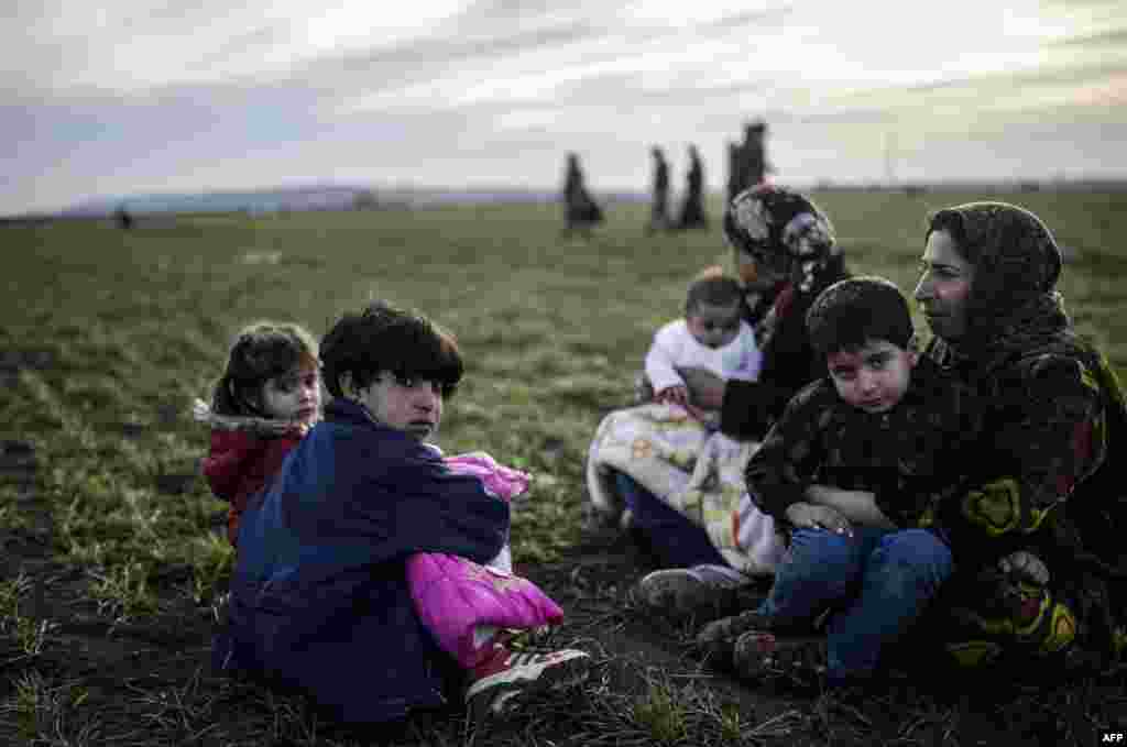 A Syrian Kurdish family sits near the Turkish-Syrian border at Suruc, in Sanliurfa province. (AFP/Bulent Kilic)