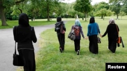 U.K. -- Yasmin (2nd L), 16, Hana (C), 16, and their friends walk in the park after finishing a GCSE exam near their school in Hackney, east London June 6, 2013. 