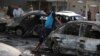 Iraqi men gather at the scene of one of two car bombs that exploded in Baghdad's Habibiyah neighborhood on May 27.