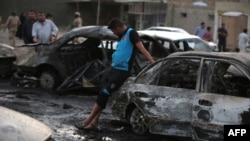 Iraqi men gather at the scene of one of two car bombs that exploded in Baghdad's Habibiyah neighborhood on May 27.