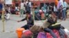 Indian migrant laborers speak on their mobile phones as they prepare to leave the region, at a railway station in Jammu, on August 7.