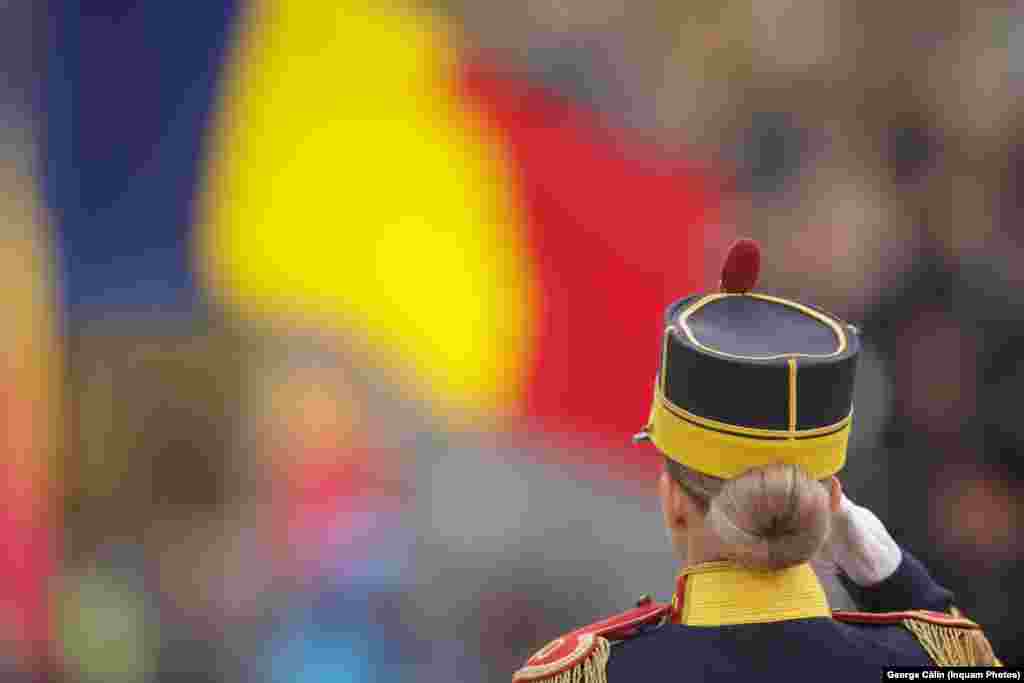 Un ofițer din Garda de Onoare a Armatei salută mulțimea adunată la parada militară de la Arcul de Triumf din București.