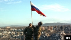 Російські військові піднімають прапор Росії в центрі Грозного. Чечня, лютий 2000 року. Російська армія взяла місто під контроль після того, як майже повністю знищила його бомбардуванням та артобстрілами.