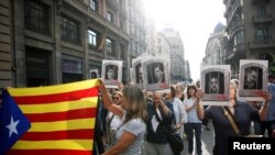 Протестующие несут флаг каталонии и фотографии каталонских сепаратистов, которым вынесли приговоры по делу о запрещенном референдуме о независимости. Испания, Барселона, 14 октября 2019 года