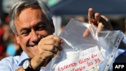 Chilean President Sebastian Pinera shows a message reading "We are fine in the refuge, the 33 of us," from the miners trapped in the San Esteban mine.