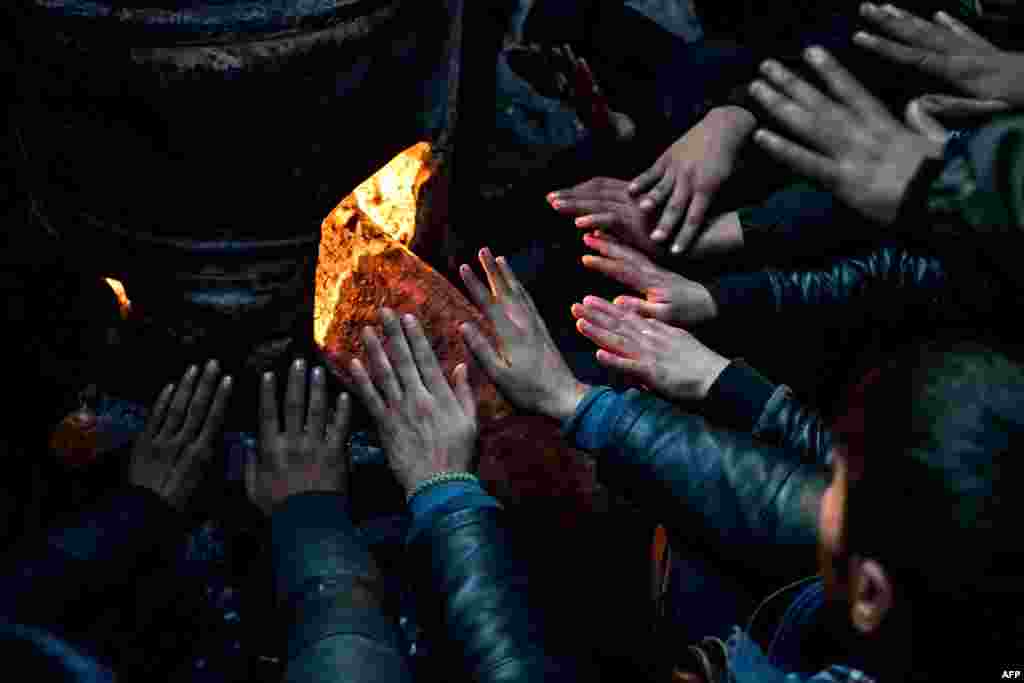 Migrants warm up at a makeshift shelter at an abandoned warehouse in Belgrade, Serbia. (AFP/Andrej Isakovic)