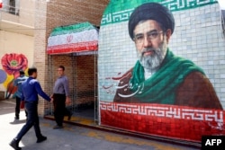A man walks past a banner depicting Iran's current supreme leader ,Ayatollah Mojtaba Khamenei. who has not been seen in public since his appointment.