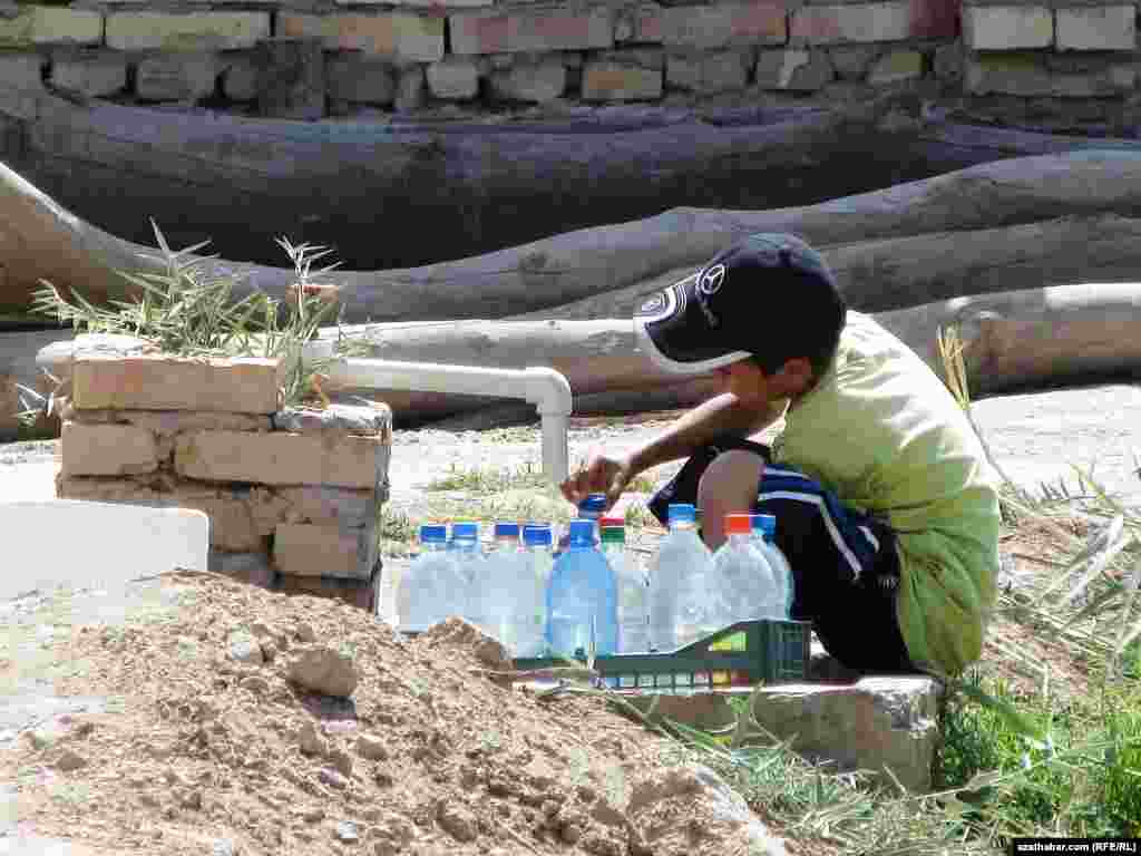 Oglanjyk ýörite suw gaplaryna agyz suwuny doldurýar.