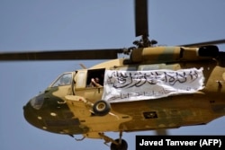 Egy tálib zászlóval díszített amerikai helikopter a 2021 szeptemberében Kandahárban összegyűlt támogatók felett, akik az amerikai csapatok Afganisztánból való kivonását ünneplik