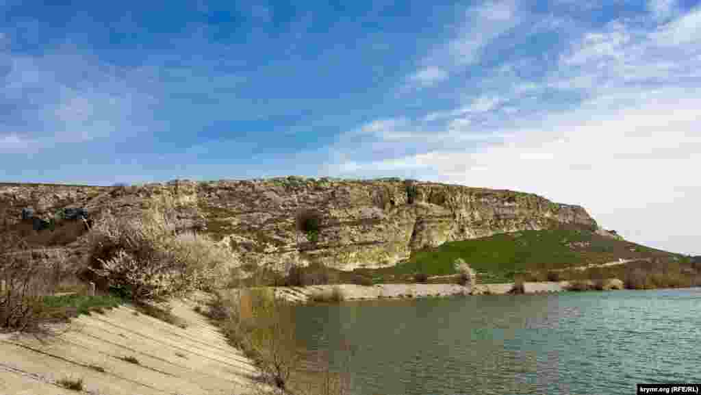Вид на Волчий грот (слева от цветущей алычи) с дамбы водохранилища на реке Бештерек
