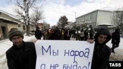 Dzhioyeva supporters hold up a sign saying, "We are people, not sheep."