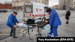 Ambulance workers transport an elderly woman -- with suspected coronavirus symptoms -- from a bus stop to a hospital in central Moscow on April 17.