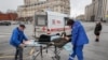 Росія: лікарі забирають жінку до карети швидкої допомоги. 17 квітня 2020 року.