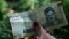 A woman holds an Iranian 100,000 rial banknote in Tajrish Bazaar in Tehran, August 1, 2019