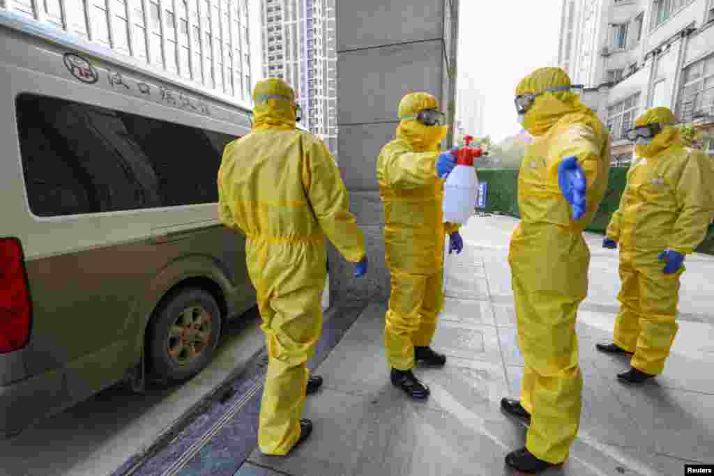CHINA -- Funeral parlour staff members in protective suits help a colleague with disinfection after they transferred a body at a hospital, following the outbreak of a new coronavirus in Wuhan, Hubei province, China January 30, 2020. 