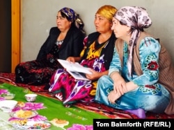 Colorfully dressed woman sit round the “dastarkhan,” the dining and seating area on the floor that serves instead of a raised table.