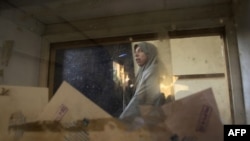 A picture taken through a ballot box shows an Egyptian woman casting her vote in the first-round runoff at a polling station in the Cairo neighborhood of Al-Manial on December 5.