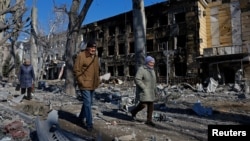 Oamenii trec pe lângă un spital de copii avariat în urma bombardamentelor din orașul Donețk, controlat de Rusia, din Ucraina, la 9 martie