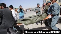 Afghan officials carry the body of a militant who died in the attack on the police station