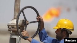 A worker adjusts a pipe at the Nassiriyah oil field, southeast of Baghdad.