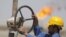 A worker adjusts a pipe at the Nassiriyah oil field, southeast of Baghdad.