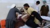 Relatives move a victim onto a bed as he receives treatment at a hospital following multiple explosions that targeted a cricket stadium in Jalalabad on May 19. Eight people were killed.
