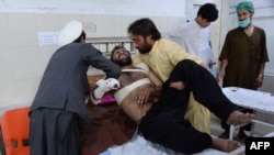 Relatives move a victim onto a bed as he receives treatment at a hospital following multiple explosions targeting a cricket stadium in Jalalabad, Afghanistan, that killed at least eight people and wounded dozens on May 18.