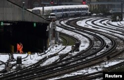 Muncitori traversează șinele acoperite de zăpadă în timpul grevei angajaților din sectorul feroviar privind salariile și condițiile de muncă, Londra, Marea Britanie, 13 decembrie 2022.