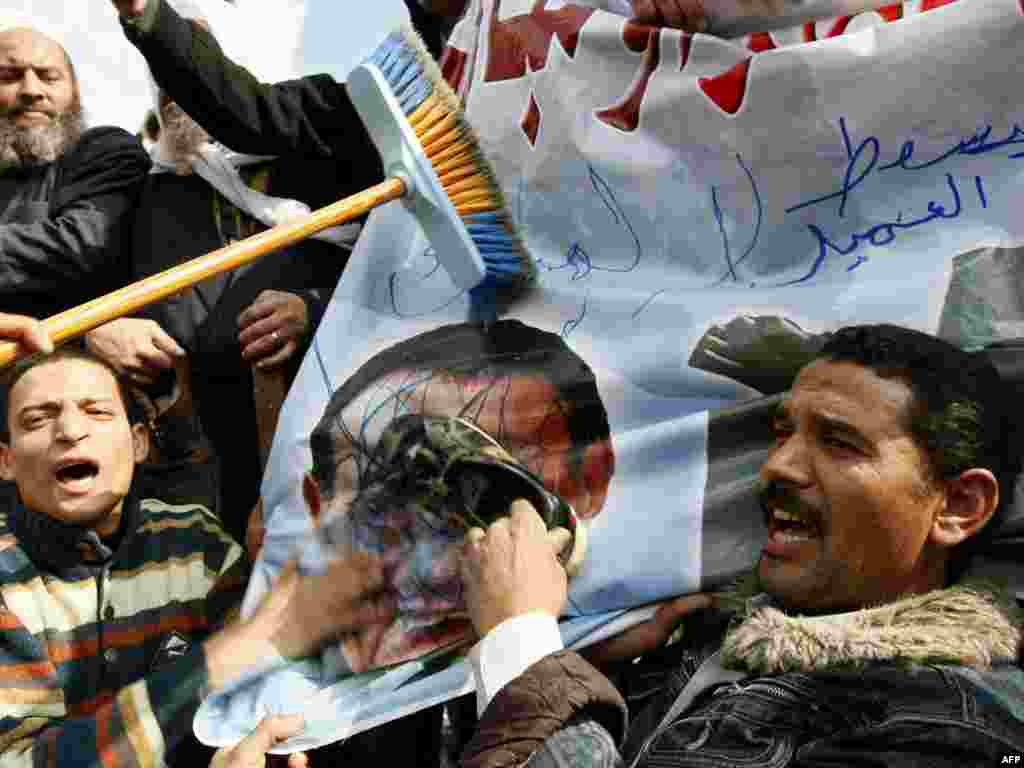 Demonstrators use a shoe and a broom to hit a picture of Hosni Mubarak in Cairo.