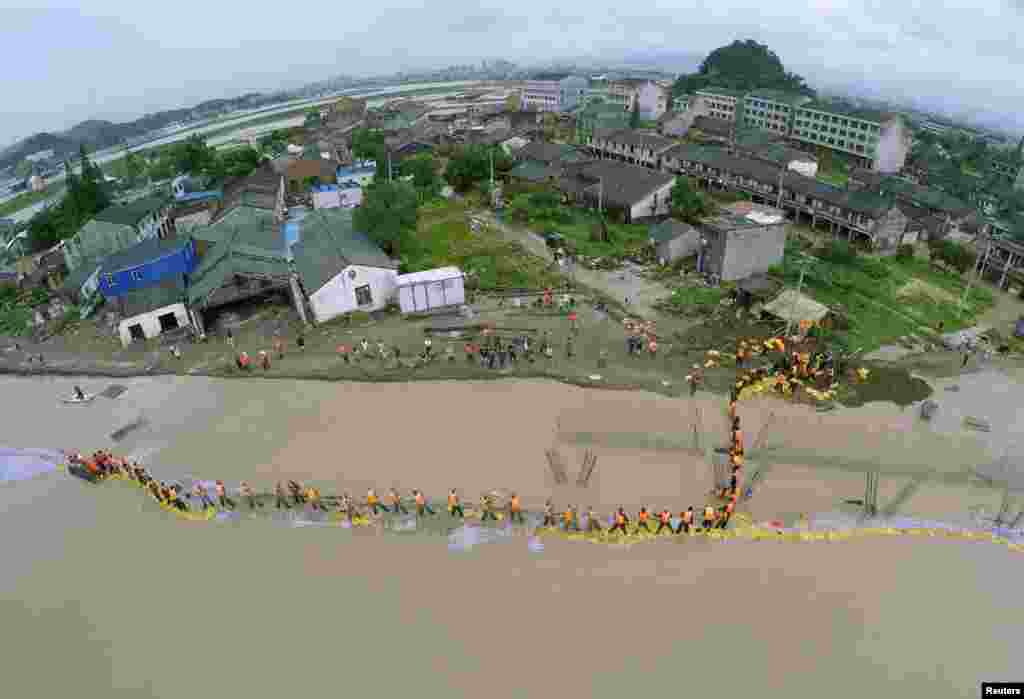 An aerial view shows People's Liberation Army soldiers and local residents placing sandbags to block floodwaters after a dam breached under the influence of Typhoon Soudelor in China's Zhejiang Province. Typhoon Soudelor battered China's east coast on August 9, killing 14 people and forcing the authorities to evacuate hundreds of thousands more. (Reuters/China Daily)