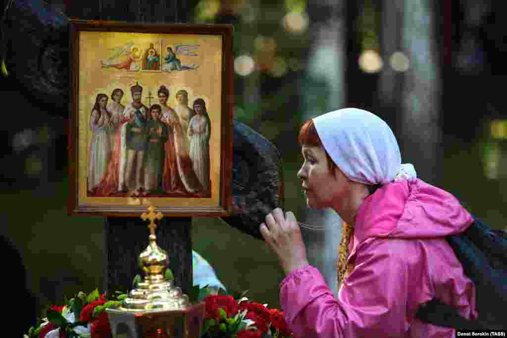 A woman kisses a cross with a portrait of the tsar, tsarina, and their five children. In 2000, the Russian Orthodox Church canonized the Romanov family. 