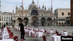 A waiter stands by empty tables outside a restaurant on Venice's St Mark's Square after the Italian government imposed a virtual lockdown on the north of Italy to try to contain a coronavirus outbreak on March 9.